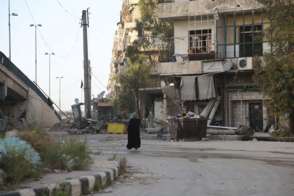 A woman walking in a destroyed area in al-Shaar neighbourhood. Photo: Hussam Kuwefatiah