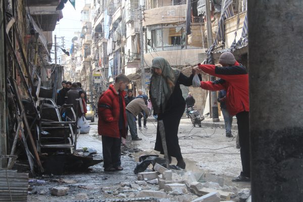 شاب يساعد إحدى السيدات التي تحاول الوصول لمنزلها الذي تعرض للقصف في حي المشهد في مينة حلب. تصوير صلاح الأشقر