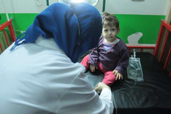 - ممرضة في احدى مشافي ريف ادلب تقوم بتغير لجرح لاحد الأطفال تصوير معهد صحافة الحرب والسلام