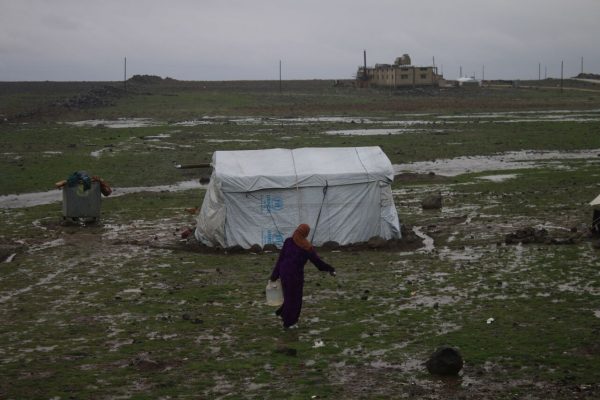 امرأة سورية تحمل كالون من الماء في مخيم الرفيد بريف محافظة القنيطرة.