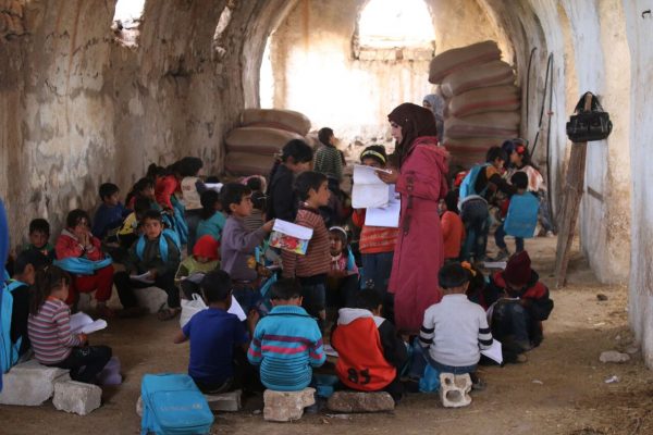 انسة سورية تعطي درساً لاطفال نازحين في مدرسة أقيمت بشكل مؤقت في بلدة المسيفرة بريف درعا الشرقي.