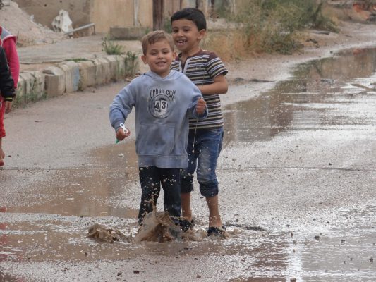 أطفال سوريون يلعبون في بركة مياه بعد نزل المطر في أحد أحياء مدينة درعا جنوب سوريا.