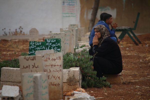 امرأة سورية تجلس بالقرب من أبنها الذي قتل بقصف لقوات النظام على أحياء مدينة درعا.
