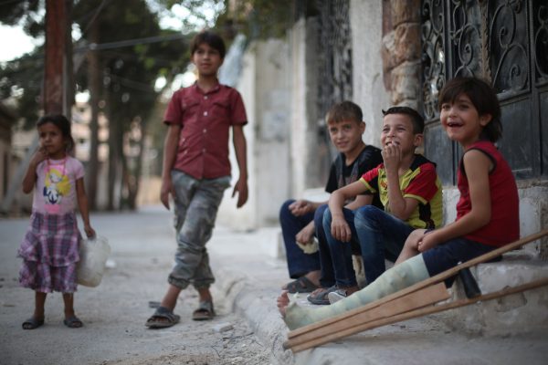 طفل متصاوب بقدمه من اثر القصف يجلس في الطريق مع اصدقائه