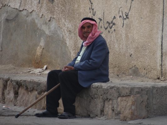: رجل مسن سوري يجلس على حافة احد الأرصفة في شوارع مدينة درعا في جنوب سوريا